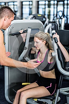 Trainer motivating woman while using exercise machine