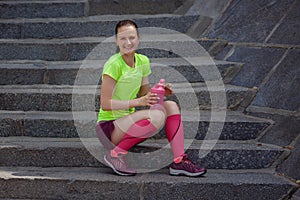 Trainer rest and drink water standing on the stairs after a joint jogging and training.