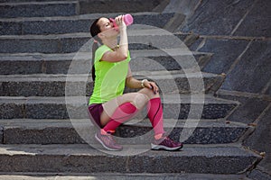 Trainer rest and drink water standing on the stairs after a joint jogging and training.