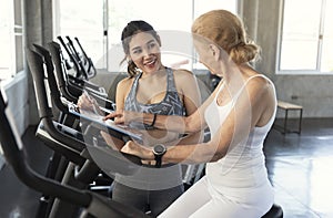 Trainer with senior woman exercising spinning bike in fitness gym. elderly healthy lifestyle concept