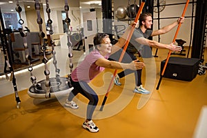 Trainer teaching middle aged woman doing sport exercise with sports sticks