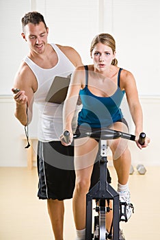 Trainer timing woman on stationary bicycle