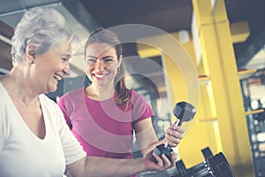 Trainer working exercise with senior woman in the gym.