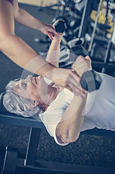 Trainer working exercise with senior woman in the gym.