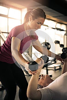 Trainer working exercise with senior woman in the gym.