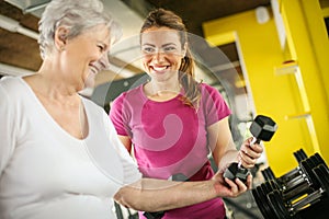 Trainer working exercise with senior woman in the gym.