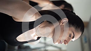 The trainer and a young woman are training in the gym lifting dumbbells pumping up the muscles of the hands