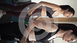 The trainer and a young woman are training in the gym lifting dumbbells pumping up the muscles of the hands. Close-up.