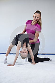 Training in the gym class. A little girl under the guidance of a trainer performs exercises. Gymnastics concept