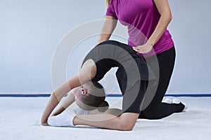 Training in the gym class. A little girl under the guidance of a trainer performs exercises. Gymnastics concept