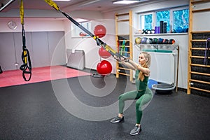 Training in the gym for the figure correction. Young woman doing fitness exercises at gym.