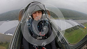 Training a new pilot for flights on plane. Gray blue fighter combat aircraft fly over green field and forest in cloudy white sky