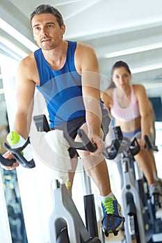 Training for the next bike race. A man and woman exercising in spinning class at the gym.