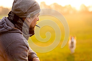 Training and obedience with a dog whistle, man is recall his pet photo