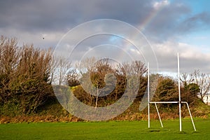 Training pitch with Irish National goal post for hurling, rugby, camogie and football, Rainbow in the blue cloudy sky. Nobody