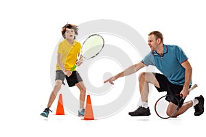 Training. Professional tennis player, coach teaches teen to play tennis isolated over white studio background. Concept