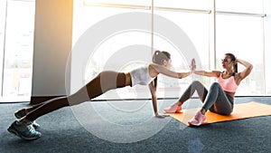 Training together. Girls doing abs workout and plank