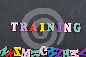TRAINING word on black board background composed from colorful abc alphabet block wooden letters, copy space for ad text. Learning