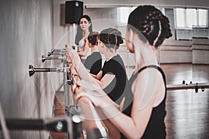 Training of young ballerinas at big light hall with mirror