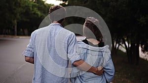 Traking footage of a young couple both in blue similar shirts are walking bonding by park. Romance, calmness, dating