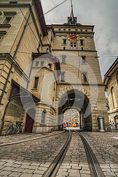 Tram railway tunnel under the baroque tower Kafigturm on a historical cobbled street. Cablecar tracks across a medieval arch