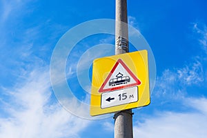 A tram stop road sign on a concrete pillar against a blue sky backdrop