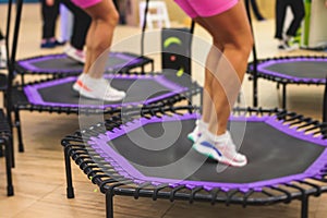 Trampoline fitness jumping training, group of young fit women in sportswear jump on trampolines, girls training with coach