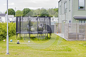Trampoline with safety net mounted on backyards with  football balls. Outdoor activity concept.