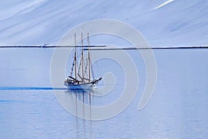 Tranquil arctic scenery with a three-masted sailboat in calm waters