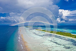 Tranquil beach landscape, palm trees, luxury villas, sand, sea. Rainbow over cloudy horizon