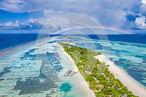 Tranquil beach landscape, palm trees, luxury villas, sand, sea. Rainbow over cloudy horizon