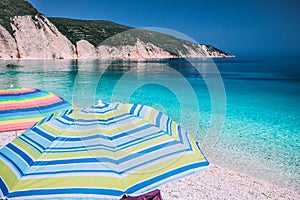 Tranquil beach scene. Picturesque landscape of mediterranean island with colorful umbrellas. Summer vacation holiday concept