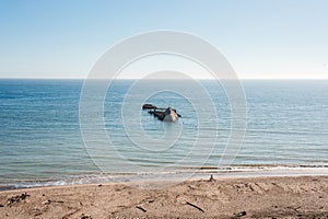 Tranquil Beach Scene with Shipwreck in Calm Waters, Clear Blue Sky
