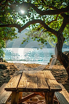 Tranquil Beach Scene with Wooden Picnic Table Under Shade Trees and Sparkling Sea in the Background