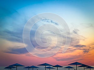 Tranquil beach sunset with silhouetted umbrellas and colorful sky