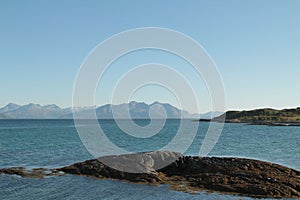 Tranquil body of water gently lapping against the rocky shoreline, illuminated in the warm sunlight