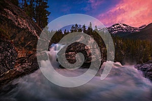 Tranquil creek through a forested landscape with two large rocks at sunset in More og Romsdal,Norway