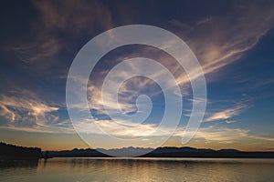 Tranquil Dawn: Reflection on Calm Lake with Blue Sky and White Clouds