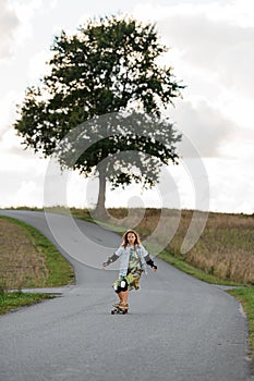 Tranquil distance. Girl's beautiful longboard ride on country road.