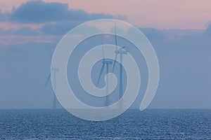 Tranquil environment scene at sea. Offshore wind farm turbines o