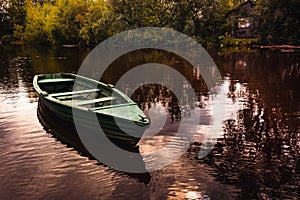 Tranquil evening landscape with river reflecting the sky and old fishing boat