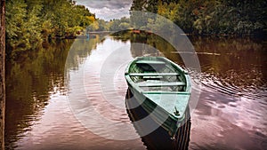 Tranquil evening landscape with river reflecting the sky and old fishing boat