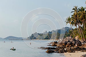 Tranquil evening at a tropical beach with people kayaking and walking along the shore