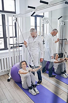 Tranquil female patient using the gym equipment for arm workout