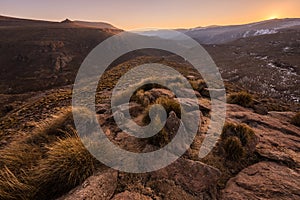 A tranquil golden snow-covered rocky mountain landscape taken at sunset