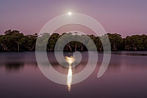 Tranquil lake, illuminated by the bright full moon in the night sky