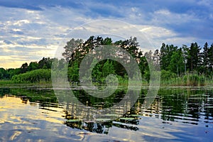 A tranquil lake scene with trees and reflections under a cloudy sky
