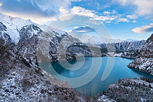 Tranquil landscape of an alpine lake, surrounded by majestic snow-covered mountains