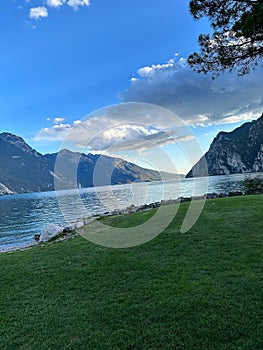 Tranquil landscape of lush green grass and large rocky outcrops by the edge of a lake