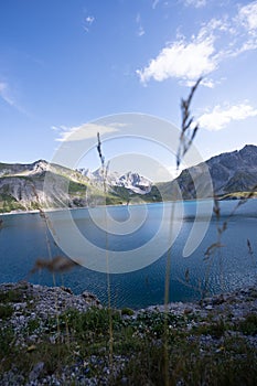 Tranquil Lunersee lake surrounded by lush green grass and jagged mountains in Austria